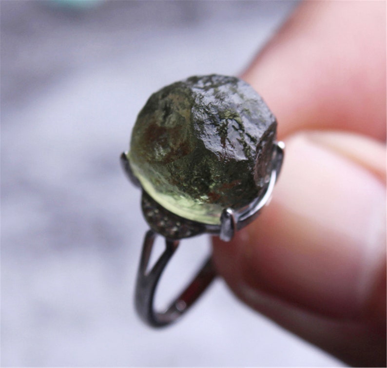 May include: A silver ring with a large, green, faceted gemstone. The gemstone is set in a silver bezel and the ring has a simple band.