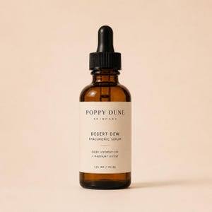 May include: A brown glass bottle of Poppy Dune Desert Dew Hyaluronic Serum with a black dropper. The label reads "Deep Hydration + Radiant Glow" and contains 30 ml.