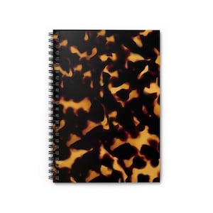 May include: A spiral bound notebook with a brown and orange tortoiseshell pattern cover.