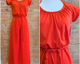 May include: A vibrant orange jumpsuit with short sleeves and a round neckline. The waist is cinched with a braided belt and matching drawstring ties. The wide-leg pants are a solid color, creating a retro, one-piece outfit.