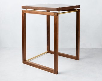 May include: A square wooden side table with a brass frame and a dark wood top.