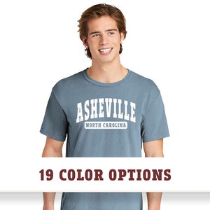 May include: A blue t-shirt with white text that reads "Asheville North Carolina".