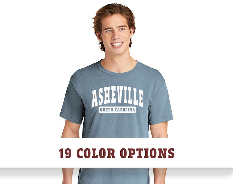 May include: A blue t-shirt with white text that reads "Asheville North Carolina".