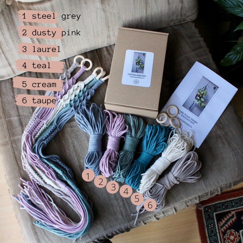 May include: A plant hanger kit with six different colored cords of macrame string, wooden rings, and instructions. The colors are steel grey, dusty pink, laurel, teal, cream, and taupe.