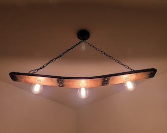May include: A rustic wooden light fixture with three light bulbs hanging from a chain. The fixture is made from a repurposed wine barrel stave.