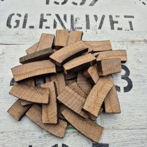 May include: A pile of brown wood chips, likely from a whiskey barrel, with a slightly curved shape. The chips are arranged in a random pattern, with some overlapping.