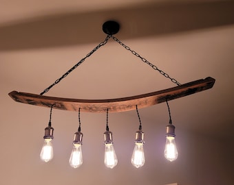 May include: A rustic wooden chandelier with five light bulbs. The chandelier is made from a reclaimed wine barrel stave and has a black chain.