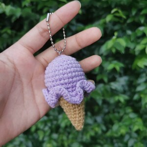May include: A purple crocheted ice cream cone keychain with a silver chain.