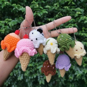 May include: A collection of eight crocheted ice cream cone keychains in various colors and flavors, including orange, pink, white, green, and purple.