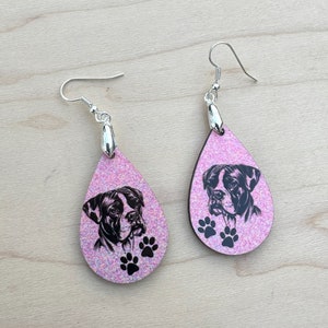 May include: A pair of pink glitter teardrop earrings with a black and white boxer dog image and paw prints.
