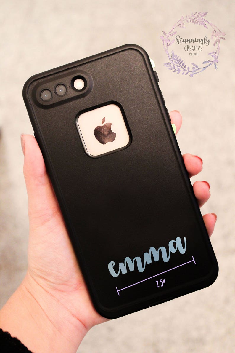 May include: Black phone case with a white apple logo and the name "emma" written in light blue cursive lettering. The case has a 2.5 inch measurement line below the name.