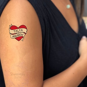 Puede incluir: Un tatuaje temporal con un coraz&oacute;n rojo y una pancarta que dice "TALYA & ANDREW".