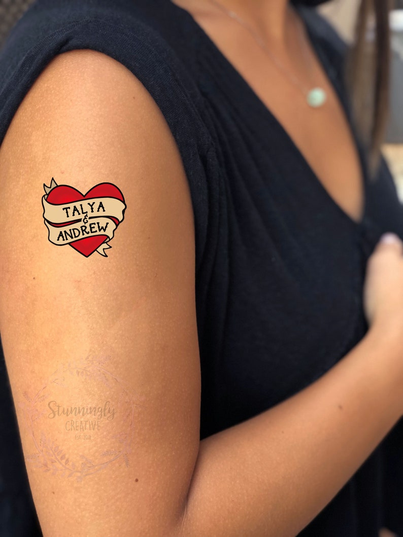 Puede incluir: Un tatuaje temporal con un coraz&oacute;n rojo y una pancarta que dice "TALYA & ANDREW".