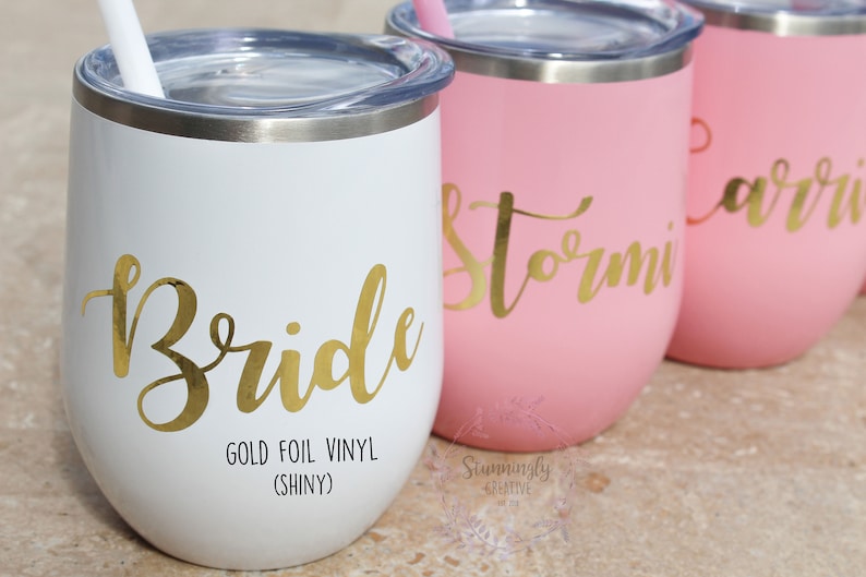 May include: Four stainless steel wine tumblers with gold foil vinyl lettering. The tumblers are white, pink, and pink. The lettering says "Bride", "Stormi", and "Carrie".