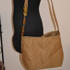 May include: A brown shoulder bag with a gold chain strap and a gold logo that says "Cavalli".