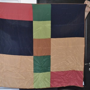 May include: A colorful patchwork fabric square with a variety of colors including red, green, brown, and beige.