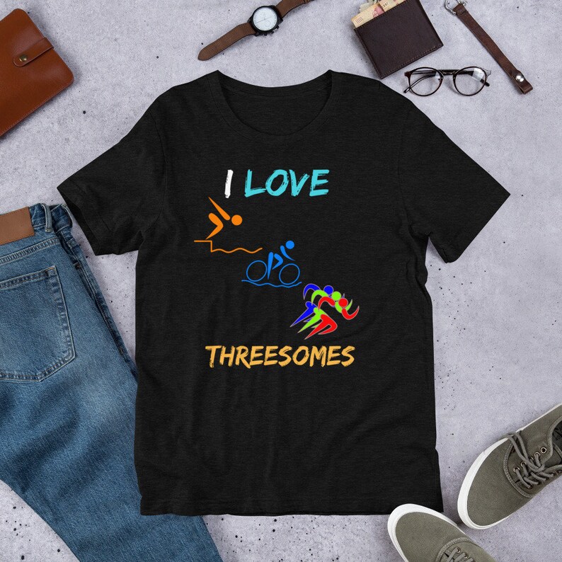 Puede incluir: Camiseta negra con el texto "I LOVE THREESOMES" y un gr&aacute;fico de tres s&iacute;mbolos de triatl&oacute;n: nataci&oacute;n, ciclismo y carrera.