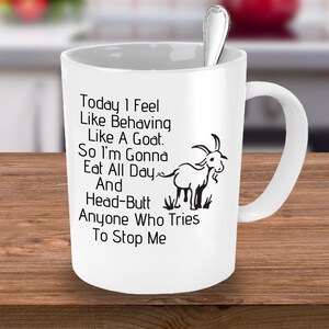 Puede incluir: Taza de caf&eacute; de cer&aacute;mica blanca con una ilustraci&oacute;n de cabra negra y texto que dice "Hoy me siento como una cabra. As&iacute; que voy a comer todo el d&iacute;a y dar cabezazos a cualquiera que intente detenerme."