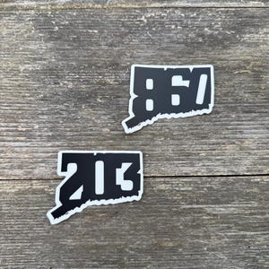 May include: Two black and white stickers shaped like the state of Connecticut. The top sticker says "860" and the bottom sticker says "203".