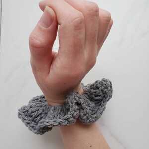 May include: Gray crocheted hair scrunchie with a ruffled design.