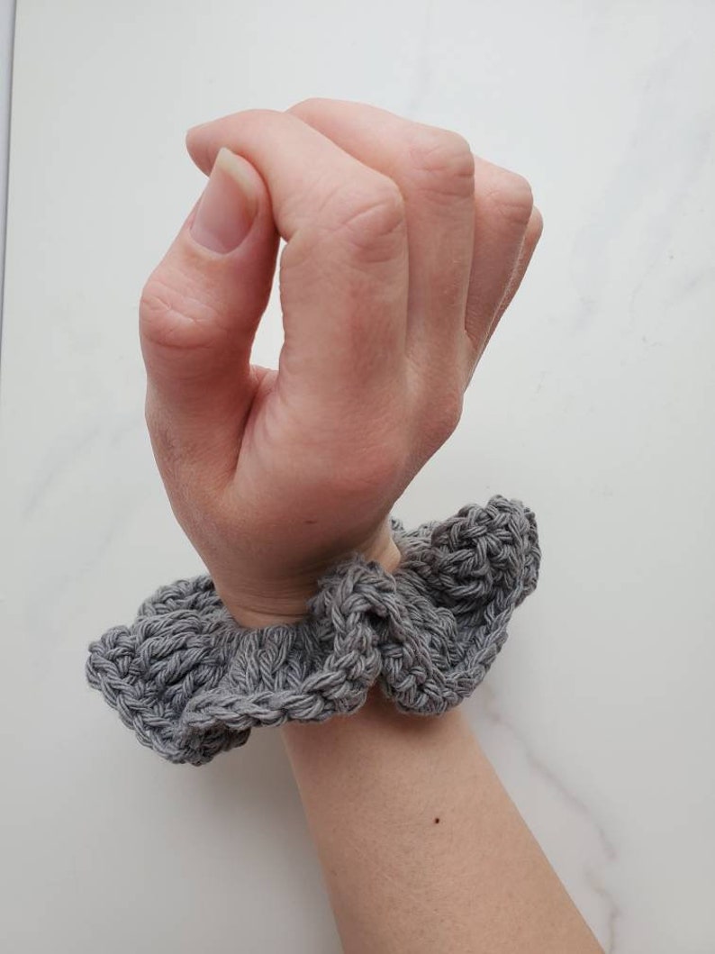 May include: Gray crocheted hair scrunchie with a ruffled design.