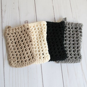 May include: Four crocheted dishcloths in beige, cream, black, and gray. The dishcloths are made with a simple open stitch pattern.