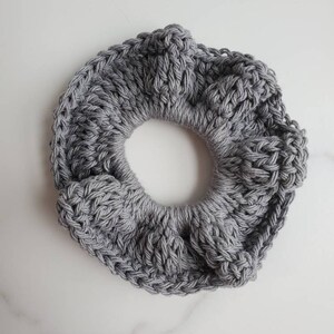 May include: A gray crocheted hair scrunchie with a textured design.