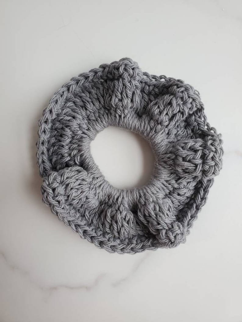 May include: A gray crocheted hair scrunchie with a textured design.