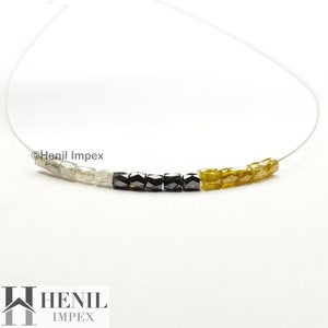 May include: A necklace featuring white, black, and yellow diamond beads. The beads are strung on a clear thread. The necklace is displayed against a white background. &copy;Henil Impex