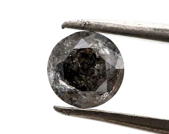 May include: A round, dark gray diamond with a faceted cut, held by tweezers.