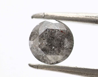 May include: A round, gray, faceted diamond with inclusions held by tweezers.