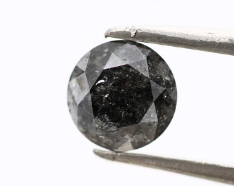 May include: A round, black diamond with a faceted cut. The diamond is held by tweezers against a white background.