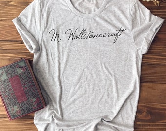 Może przedstawiać: Jasnoszary t-shirt z nadrukiem "M. Wollstonecraft" w kolorze czarnym na przodzie.