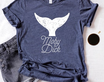 May include: A navy blue t-shirt with a white whale tail graphic and the text "Moby Dick" in a cursive font.