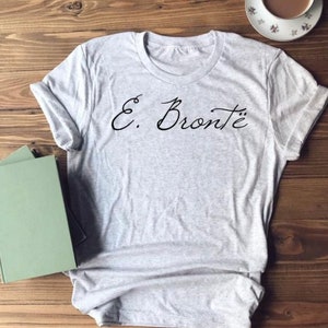 Puede incluir: Una camiseta gris con el texto "E. Bront&euml;" en escritura cursiva negra.