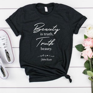 May include: Black t-shirt with white text that reads "Beauty is truth, Truth beauty."  The text is in a cursive font and is followed by "John Keats" in a smaller font.
