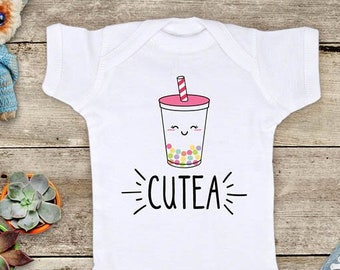 May include: White baby onesie with a cartoon illustration of a boba tea cup with a smiling face and the text "CUTEA" on the front.