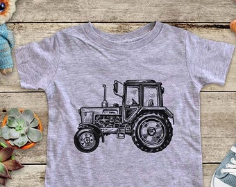 May include: A gray t-shirt with a black and white illustration of a tractor. The tractor has a large front tire and a smaller back tire. The t-shirt is a great gift for a child who loves farm equipment.