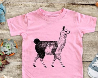May include: A pink toddler t-shirt with a black and white illustration of a llama. The llama is standing on all four legs and has a long neck and a fluffy tail.