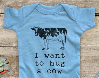 May include: A light blue baby onesie with a black and white cow illustration and the text "I want to hug a cow".