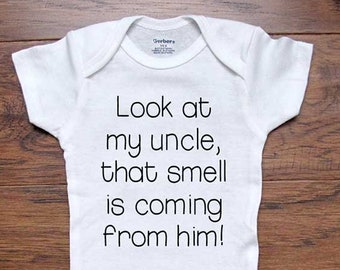 May include: White baby onesie with black text that reads "Look at my uncle, that smell is coming from him!"