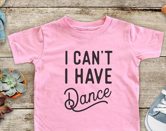 May include: Pink toddler t-shirt with the text "I can't I have Dance" in black lettering.