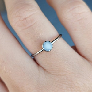 May include: A silver ring with a white opal stone.