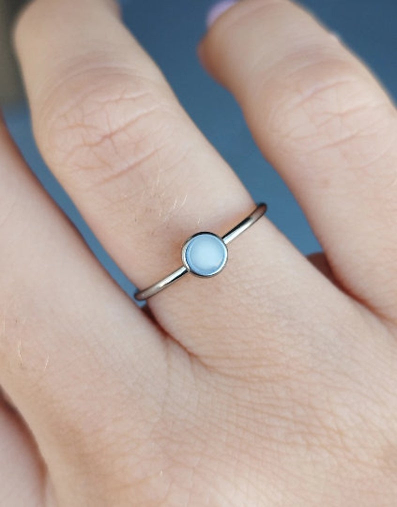 May include: A silver ring with a white opal stone.