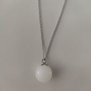 May include: A silver chain necklace with a white orb pendant.