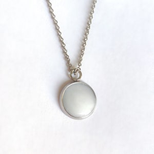 May include: A silver chain necklace with a white round pendant.