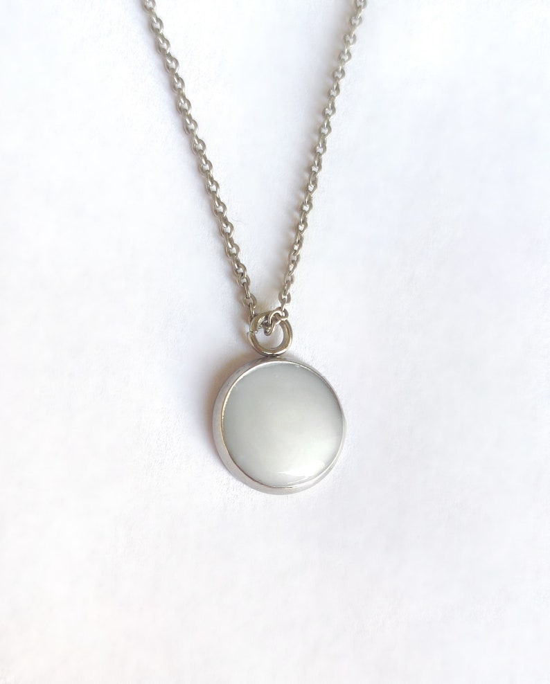May include: A silver chain necklace with a white round pendant.