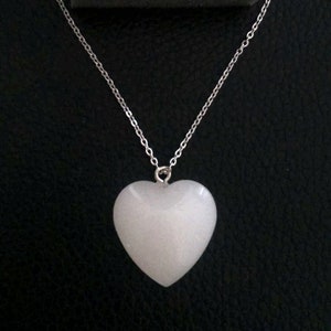 May include: A white heart-shaped pendant on a silver chain necklace.