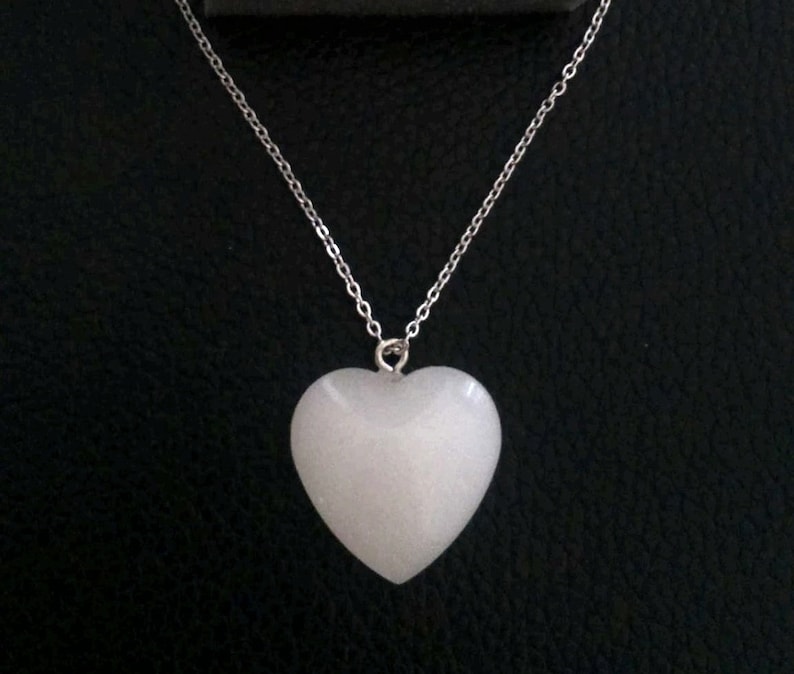 May include: A white heart-shaped pendant on a silver chain necklace.
