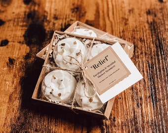 May include: A box of four white shower steamers with a brown paper tag that reads "Relief" Eucalyptus & Menthol Shower Steamers.  Designed to relax & take a deep breath. Net weight 1oz.